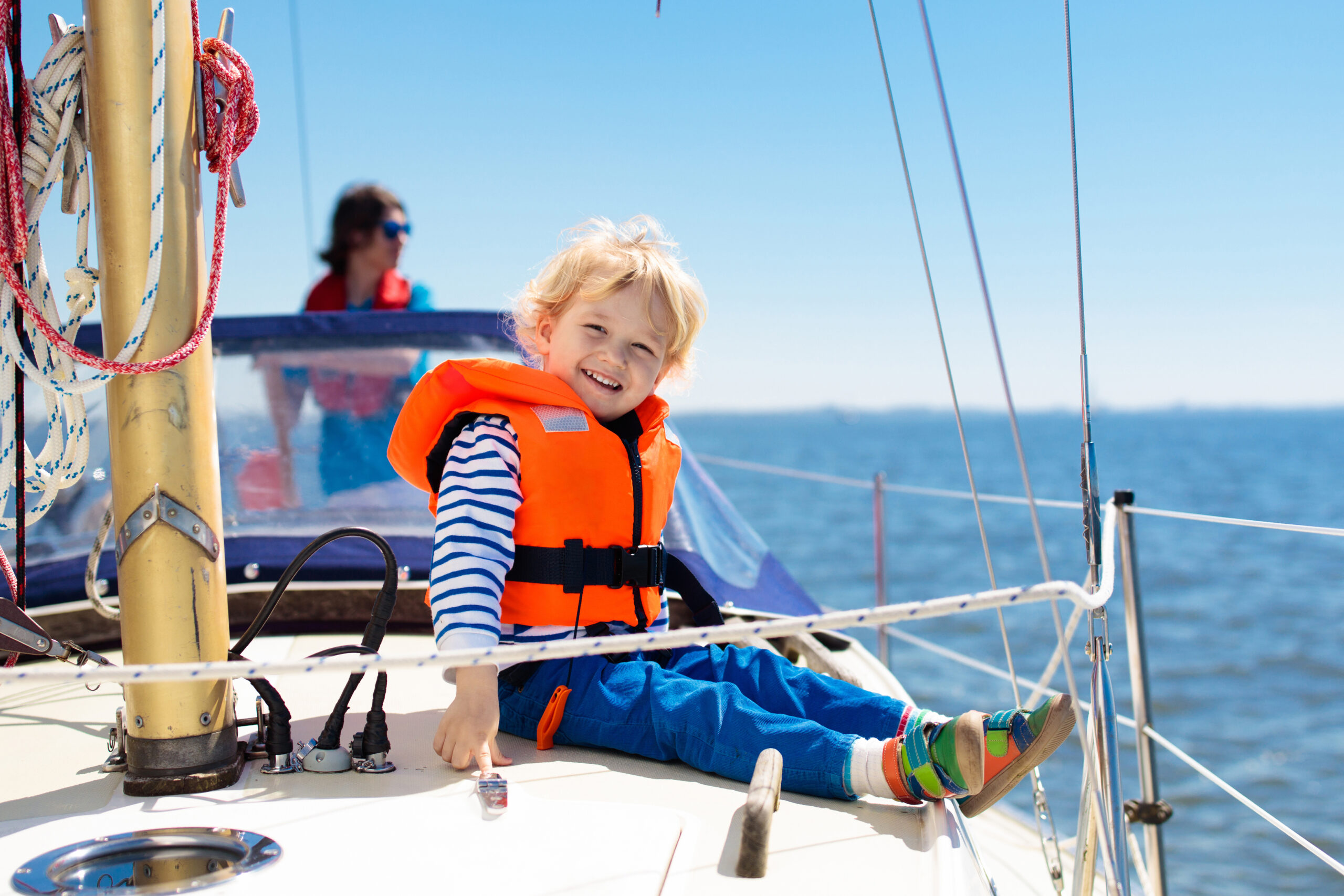 little boy in life jacket sitting on a boat in the water