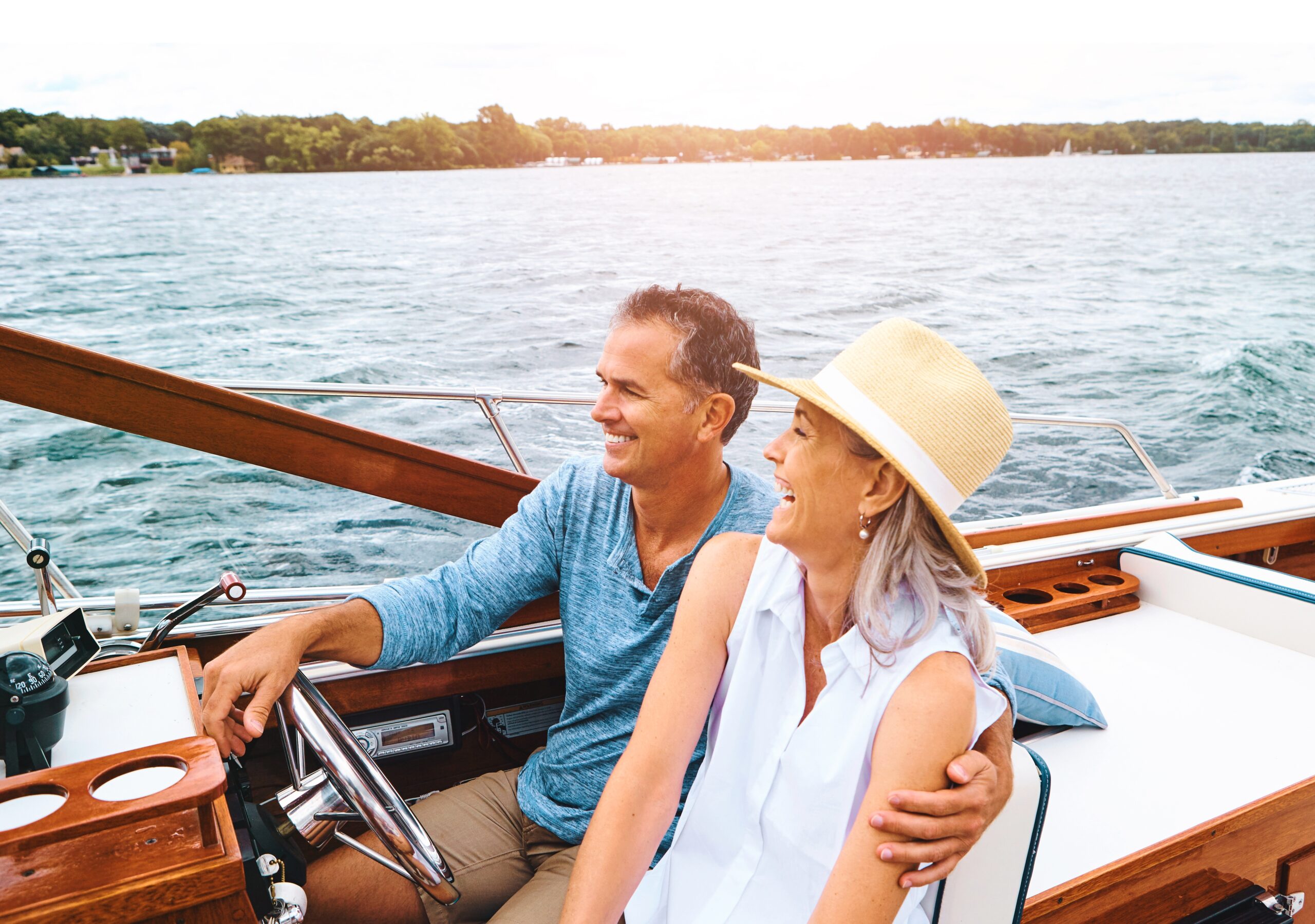 man and woman cruising through the water on their boat. Smiling and laughing. 