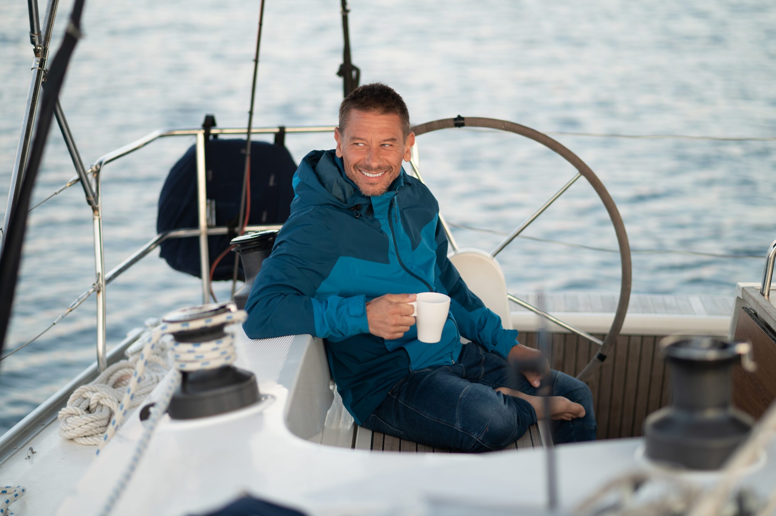 man on a boat with a warm drink and blue jacket