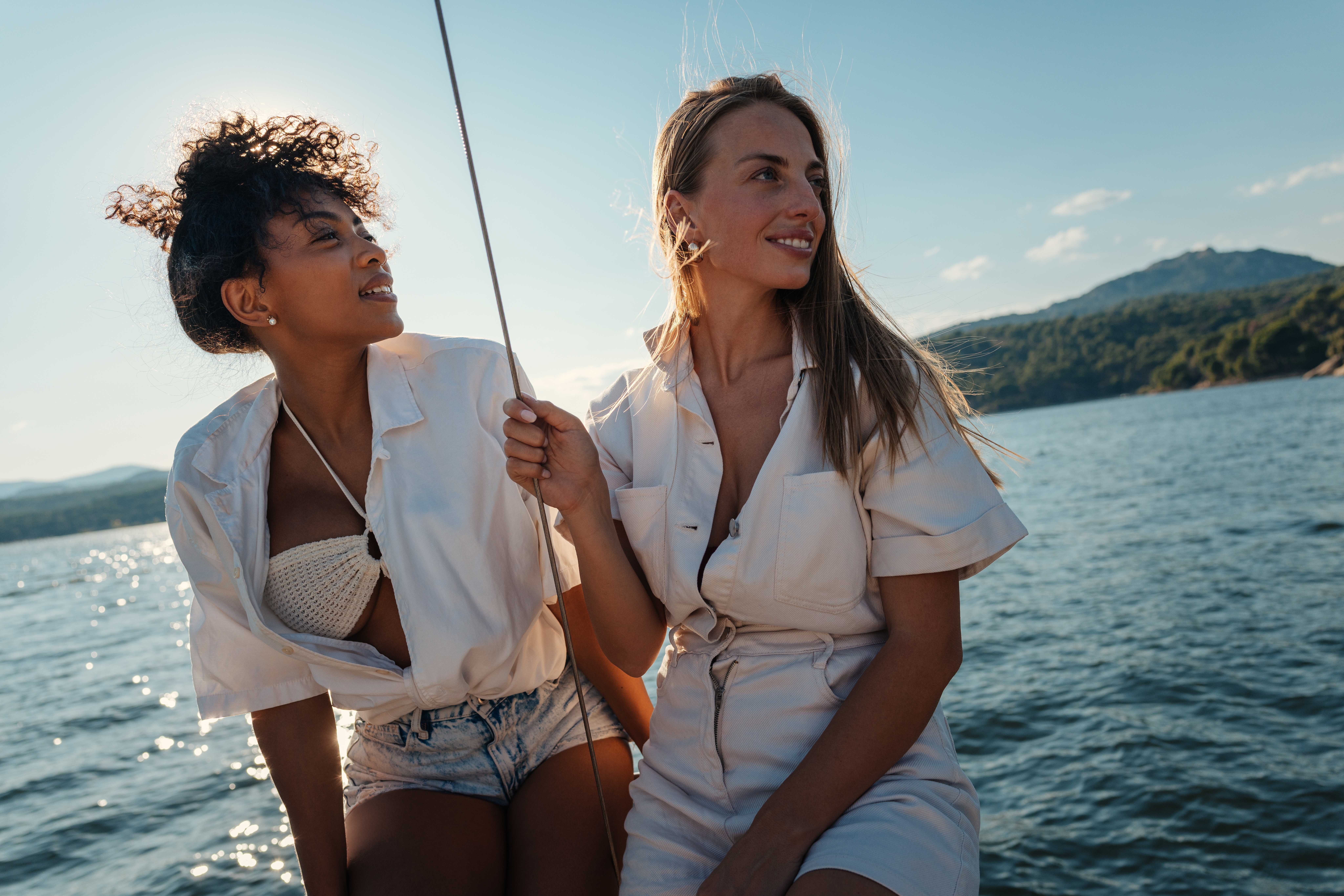 two women wearing white and sailing on the water 